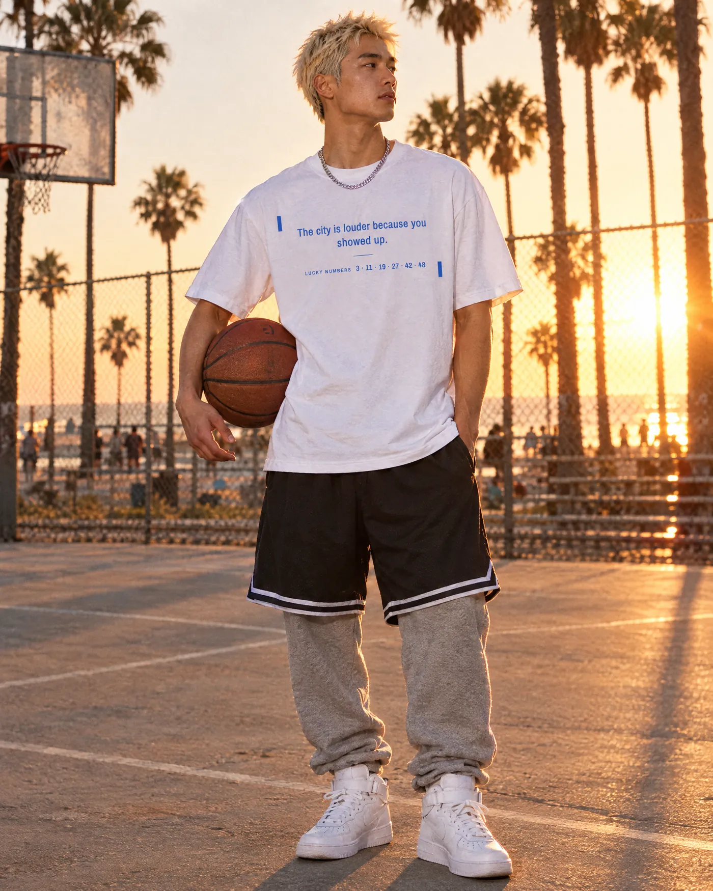 Man holding a basketball in the Fortune Cookie Shirt on a Venice Beach court at sunset